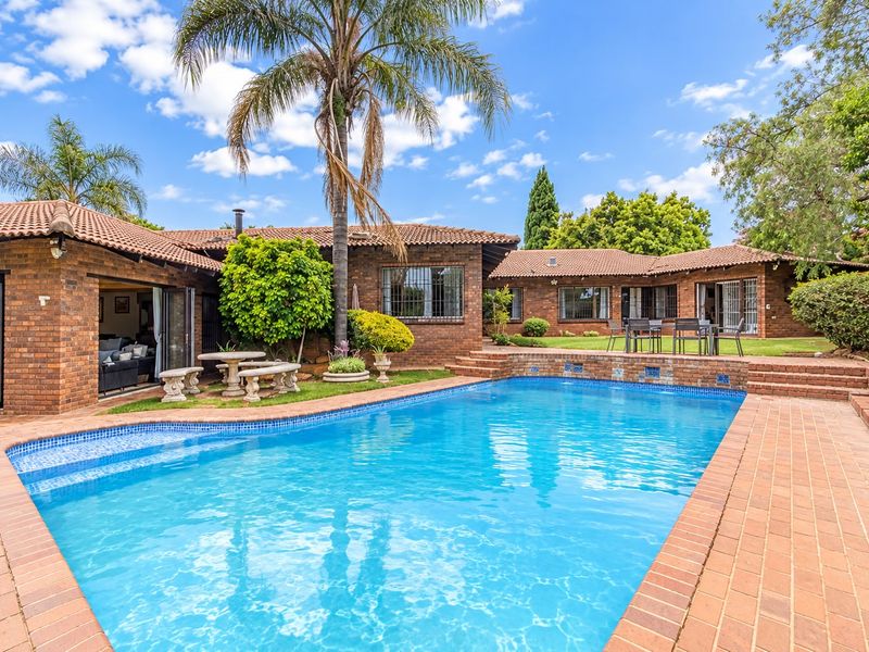 A well-maintained outdoor pool area featuring brick paving, a tiled roof structure, and direct access to the home through sliding doors.