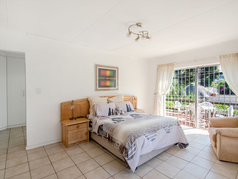 Spacious bedroom featuring tiled flooring, built-in cupboards, and a sliding door providing direct access to an outdoor patio area.