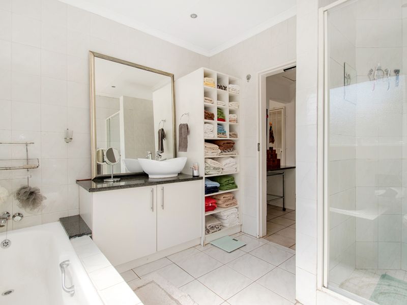 A well-maintained bathroom featuring a built-in vanity with a vessel sink, granite countertop, separate shower enclosure, and a bathtub with tiled finishes.