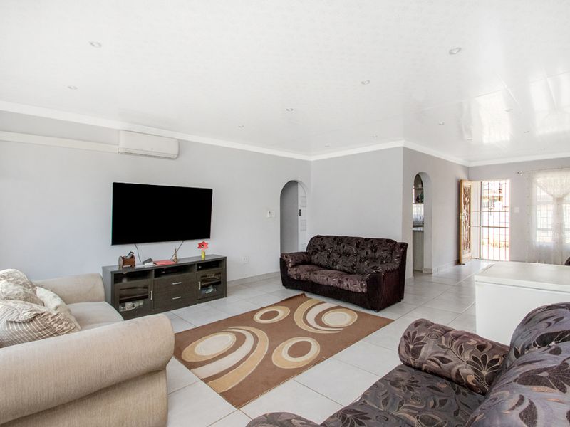 Spacious living room featuring tiled flooring, recessed lighting, and an air conditioning unit, with an open-plan layout leading to other areas of the home.