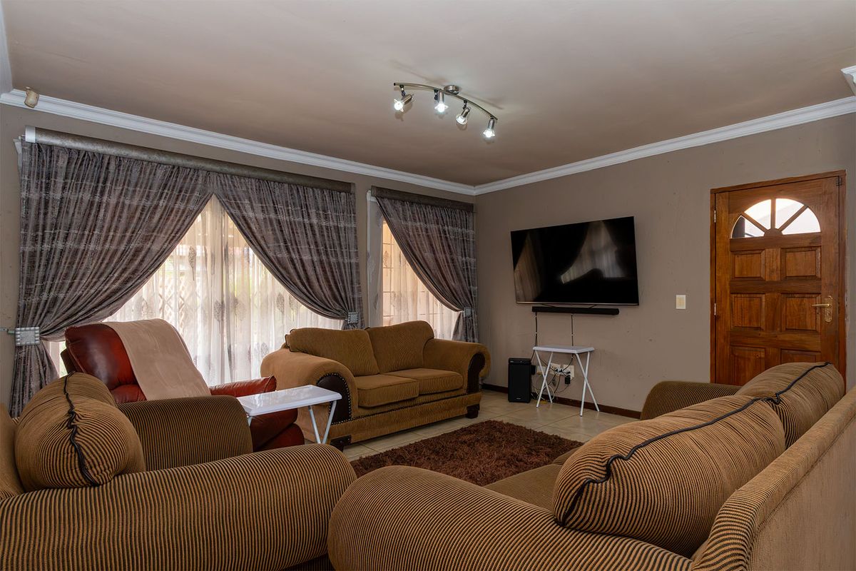 A comfortable living room featuring tiled flooring, crown molding, and track lighting, providing a functional space for relaxation and entertainment.
