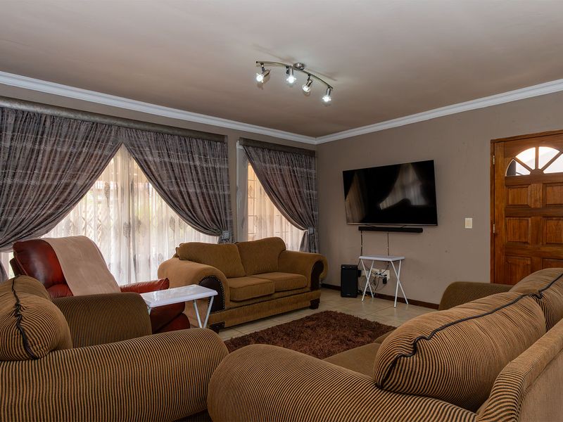 A comfortable living room featuring tiled flooring, crown molding, and track lighting, providing a functional space for relaxation and entertainment.