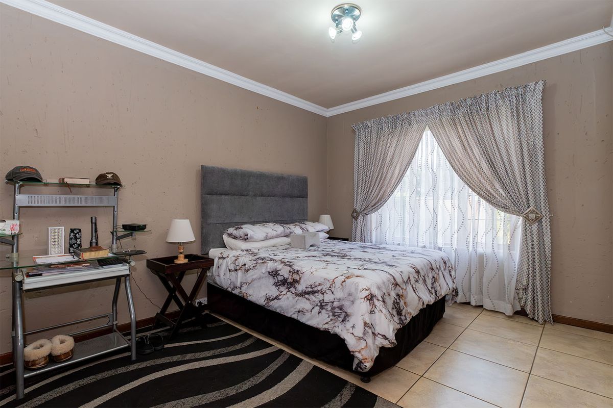 A bedroom featuring tiled flooring, ceiling cornice, and neutral wall tones, offering a functional space ready for cosmetic updates.