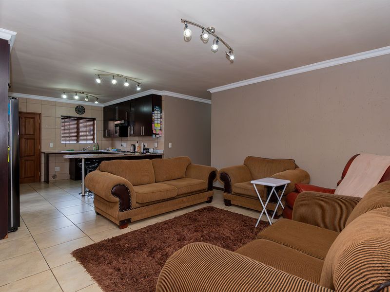 Open plan living area featuring a kitchen with dark cabinetry, a breakfast island, and tiled flooring throughout the combined space.
