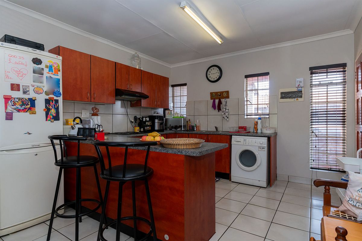 A functional kitchen featuring laminate cabinetry, granite countertops, tiled flooring, and a built-in hob with an extractor fan.