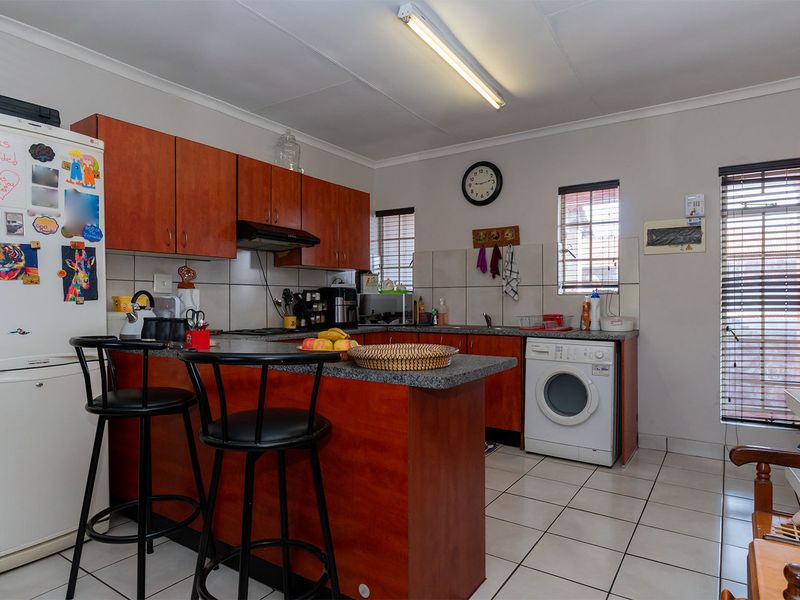 A functional kitchen featuring laminate cabinetry, granite countertops, tiled flooring, and a built-in hob with an extractor fan.