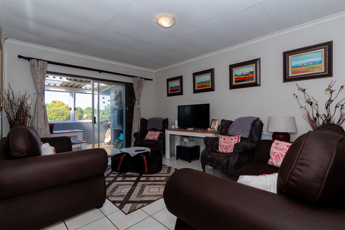A comfortable living room featuring tiled flooring and a sliding glass door that provides access to an outdoor patio area.