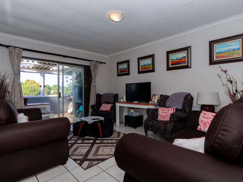 A comfortable living room featuring tiled flooring and a sliding glass door that provides access to an outdoor patio area.