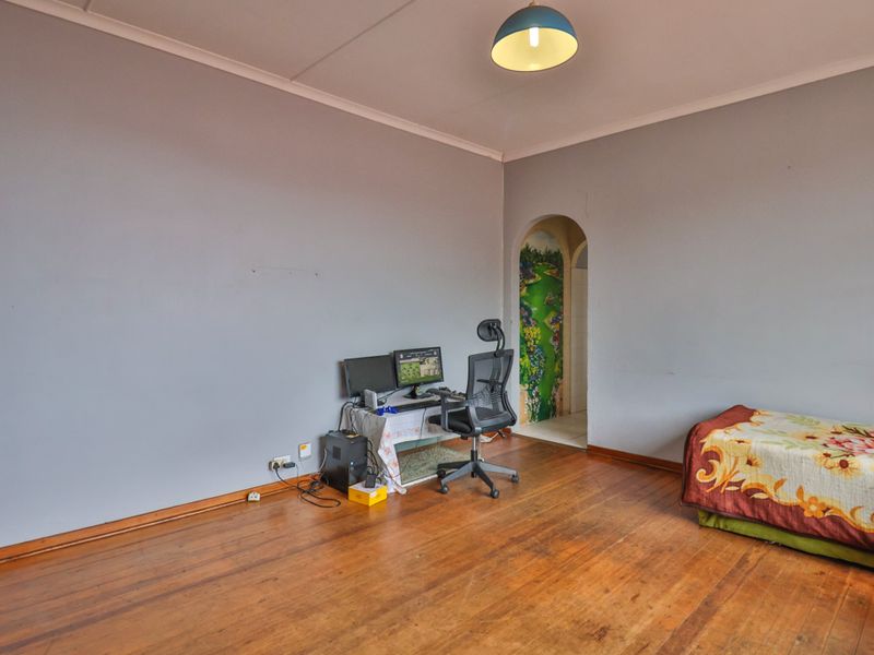 A bedroom featuring original hardwood flooring, coved ceilings, and a unique arched doorway leading to an adjacent space.