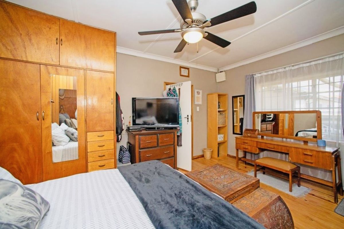 A bedroom featuring built-in wooden cabinetry, a ceiling fan, and wooden flooring, offering a functional and traditional living space.