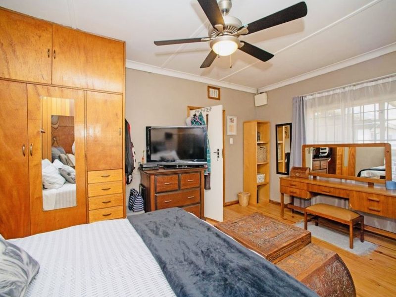 A bedroom featuring built-in wooden cabinetry, a ceiling fan, and wooden flooring, offering a functional and traditional living space.