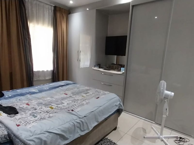 A well-maintained bedroom featuring modern built-in cupboards with high-gloss finishes, tiled flooring, and recessed ceiling lighting.