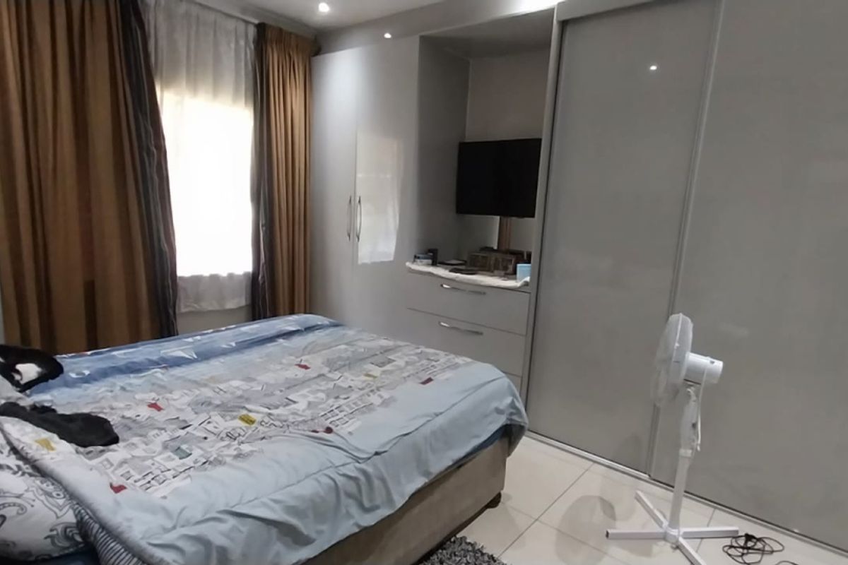 A well-maintained bedroom featuring modern built-in cupboards with high-gloss finishes, tiled flooring, and recessed ceiling lighting.