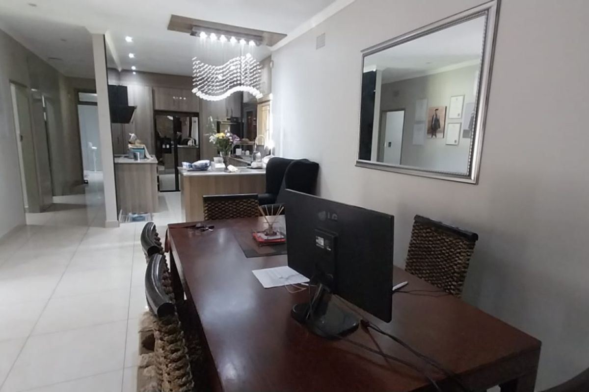 An open-plan living and dining area featuring tiled floors, recessed lighting, and a modern kitchen with built-in cabinetry and appliances.