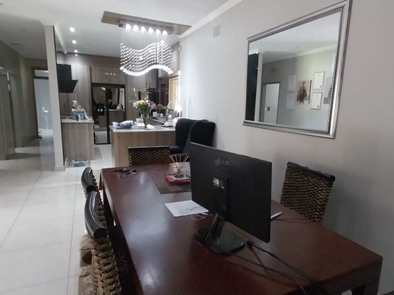 An open-plan living and dining area featuring tiled floors, recessed lighting, and a modern kitchen with built-in cabinetry and appliances.