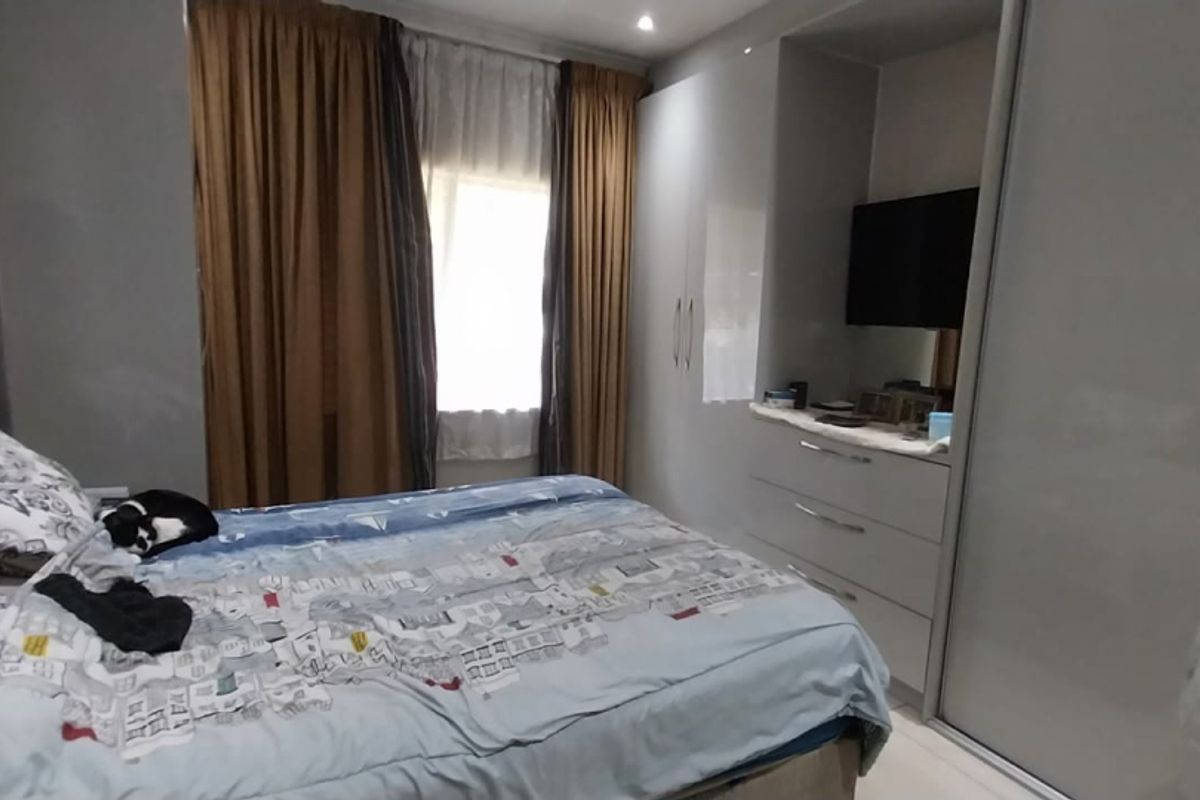 A well-maintained bedroom featuring modern built-in cupboards with sliding doors and recessed ceiling lighting.