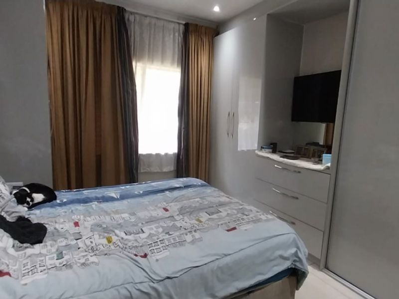 A well-maintained bedroom featuring modern built-in cupboards with sliding doors and recessed ceiling lighting.