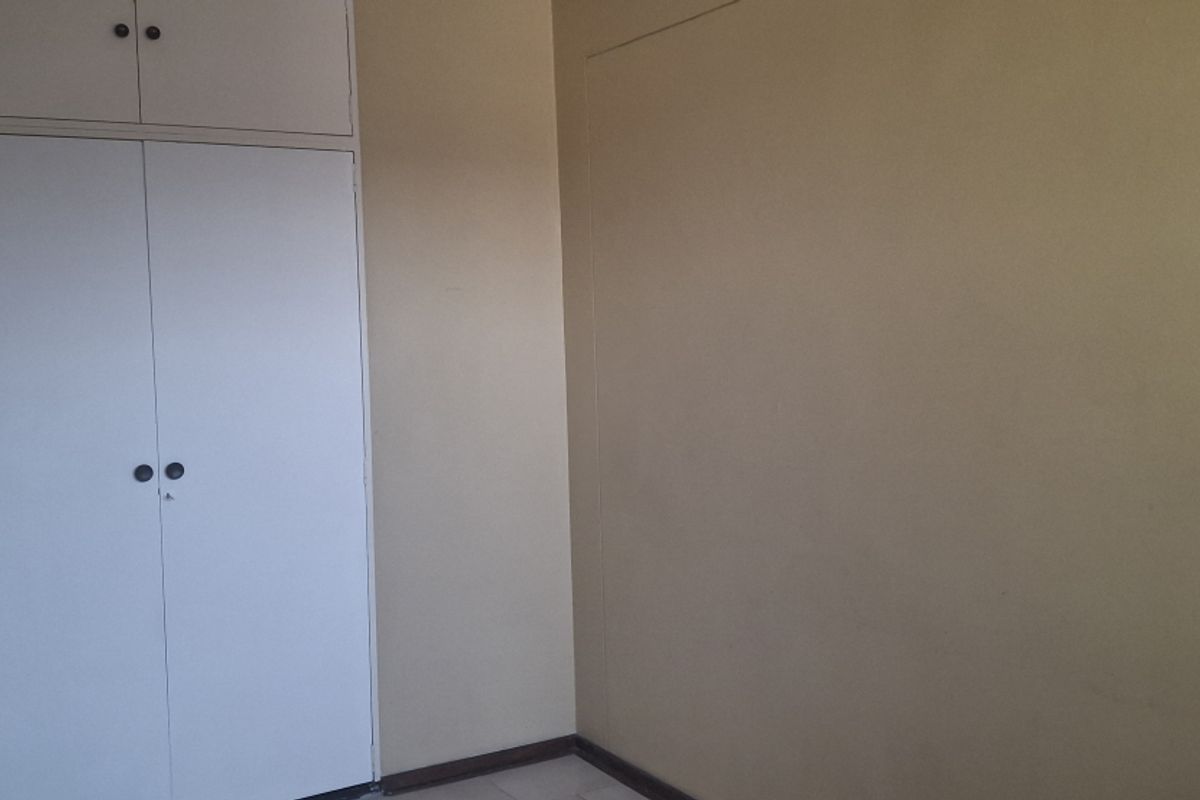A vacant bedroom featuring neutral wall finishes and built-in cupboards with additional overhead storage space.
