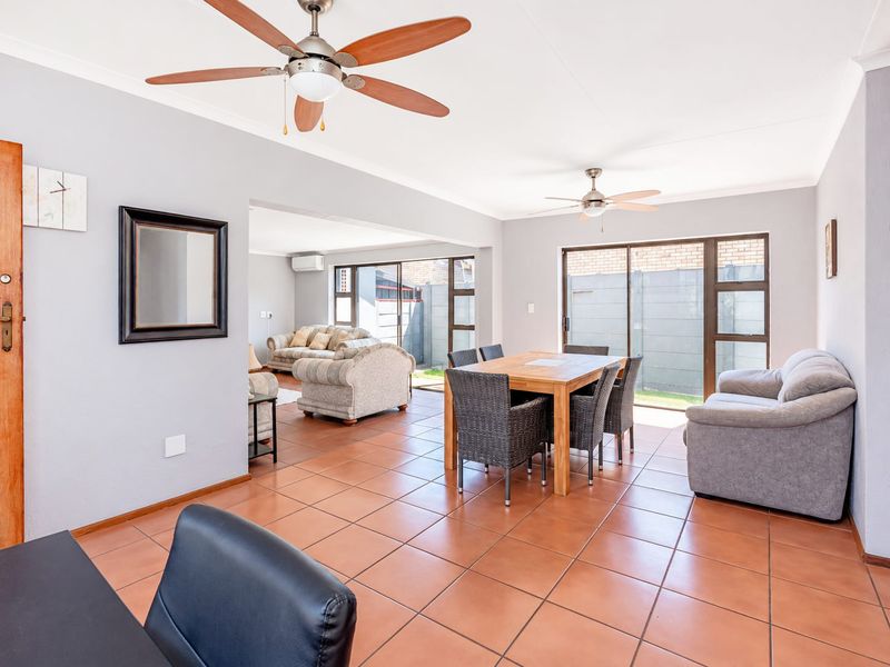 Spacious open-plan living and dining area featuring ceramic tile flooring, dual ceiling fans, and large sliding glass doors providing natural light and garden access.