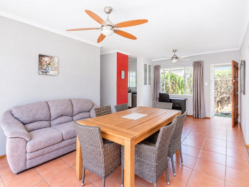 Open plan living and dining area featuring tiled flooring, ceiling fans, and direct access to the exterior through a side door.