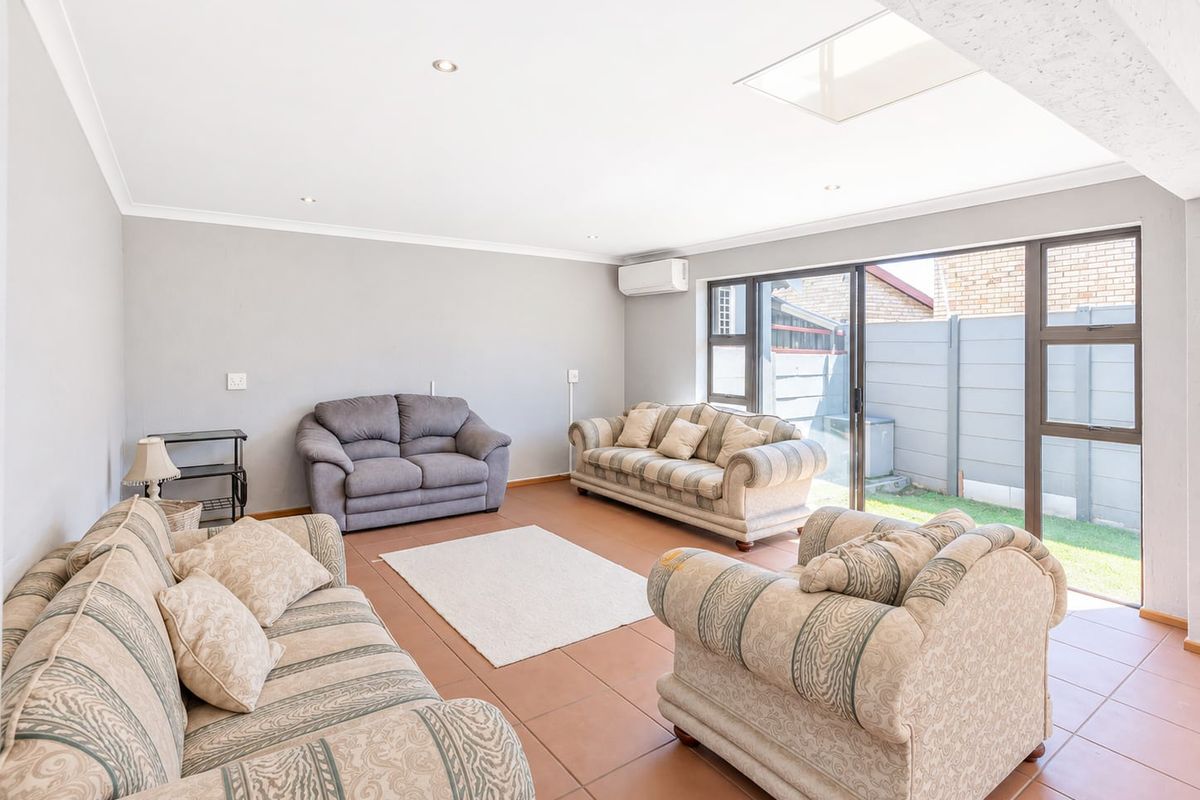 Spacious living room featuring tiled flooring, a skylight, recessed lighting, and large sliding glass doors providing access to the rear garden area.