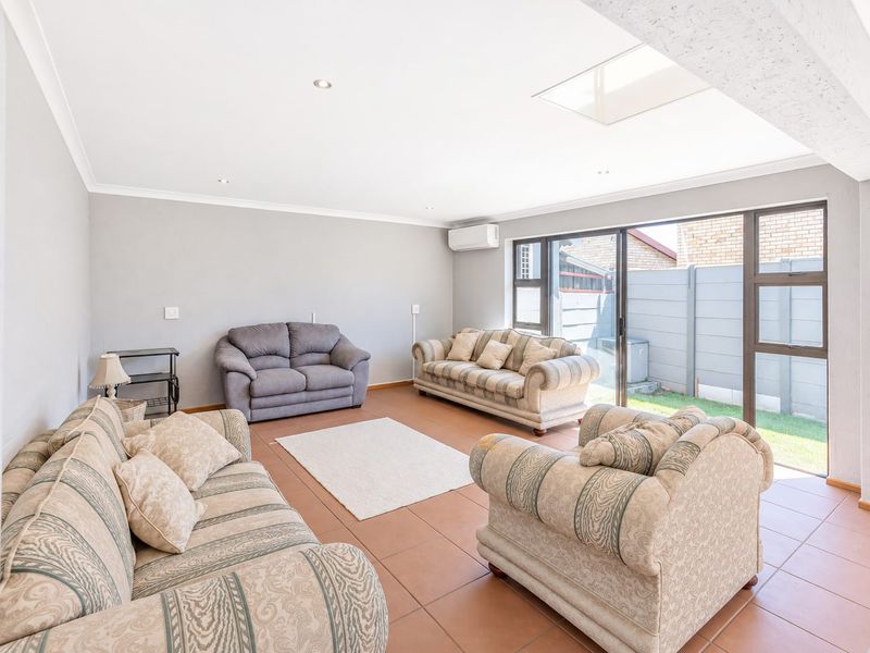 Spacious living room featuring tiled flooring, a skylight, recessed lighting, and large sliding glass doors providing access to the rear garden area.