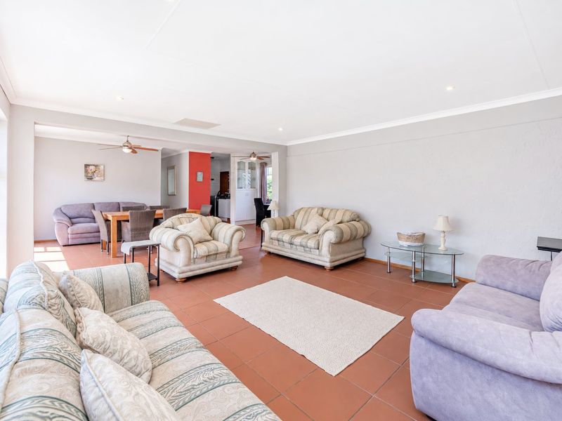 Spacious open-plan living and dining area featuring neutral wall tones, tiled flooring, and integrated ceiling lighting, providing a versatile layout for family living.