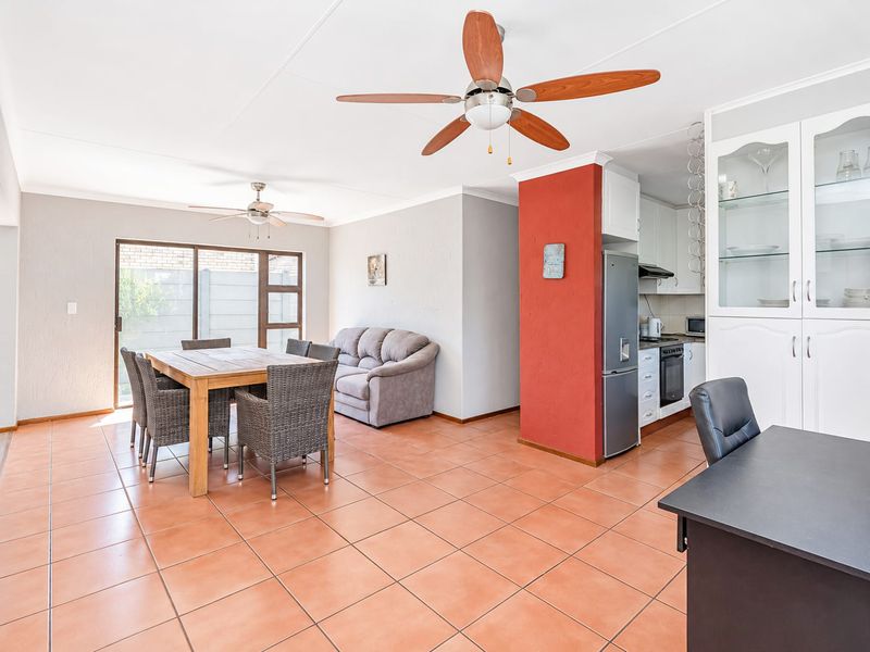 Open-plan living and dining area featuring tiled floors, ceiling fans, and a functional kitchen with built-in cabinetry and appliances.
