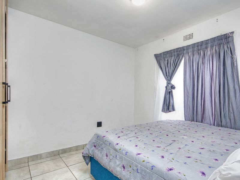 A functional bedroom featuring tiled flooring and a built-in wardrobe, providing a clean and practical living space.