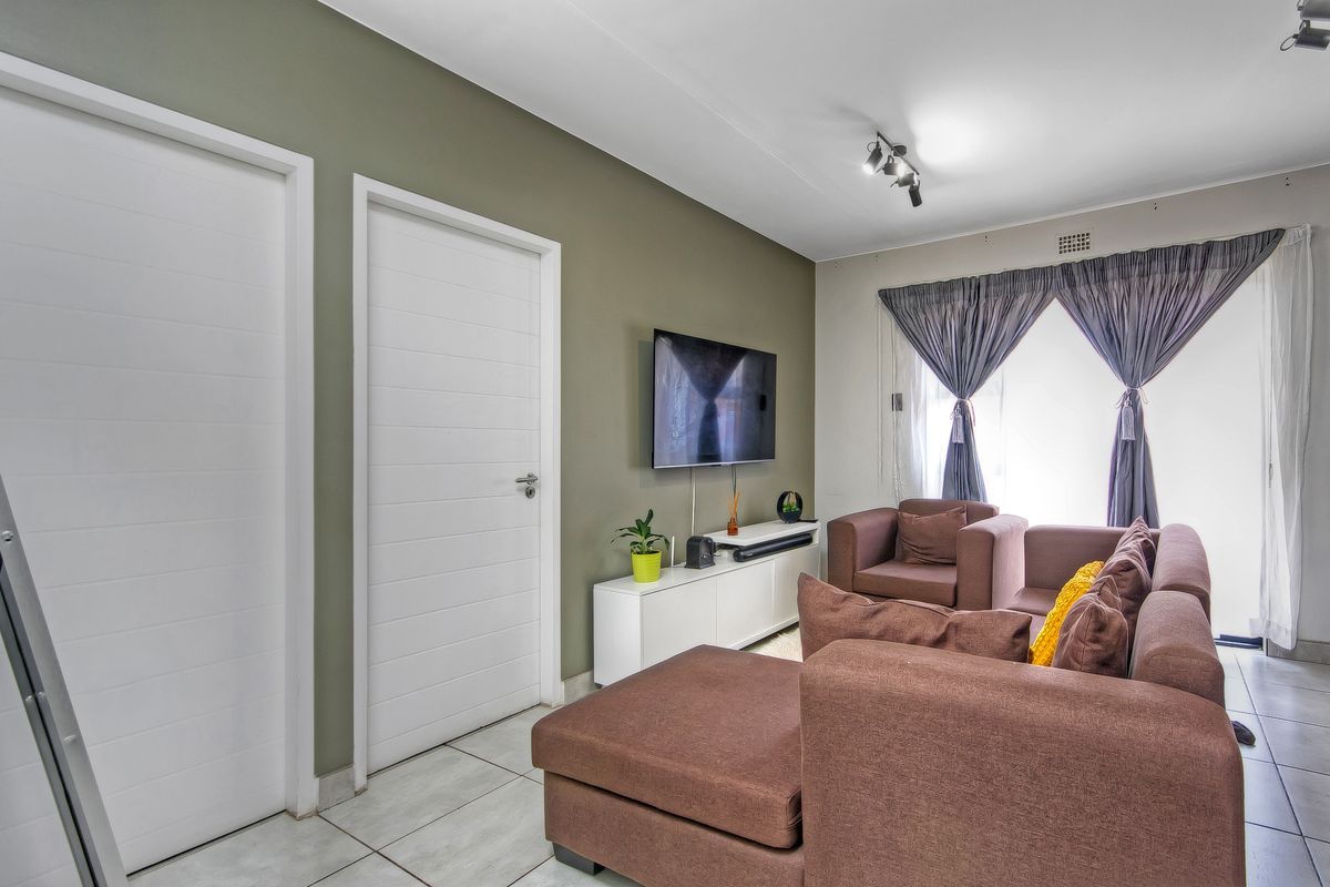 A well-maintained living room featuring neutral wall tones, tiled flooring, and modern internal doors, providing a comfortable and functional living space.