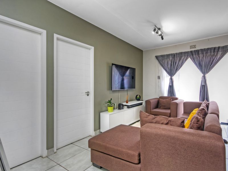 A well-maintained living room featuring neutral wall tones, tiled flooring, and modern internal doors, providing a comfortable and functional living space.