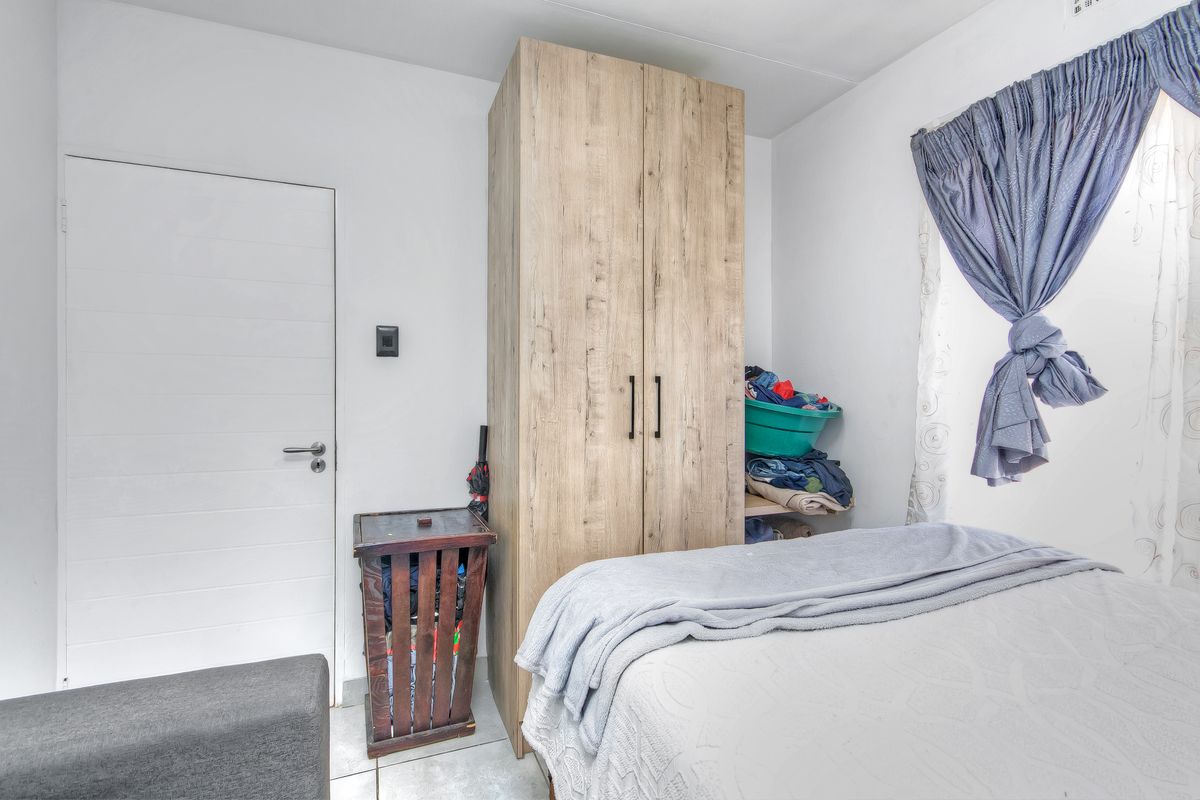 A bedroom featuring tiled flooring and a built-in wooden wardrobe, providing functional storage space.