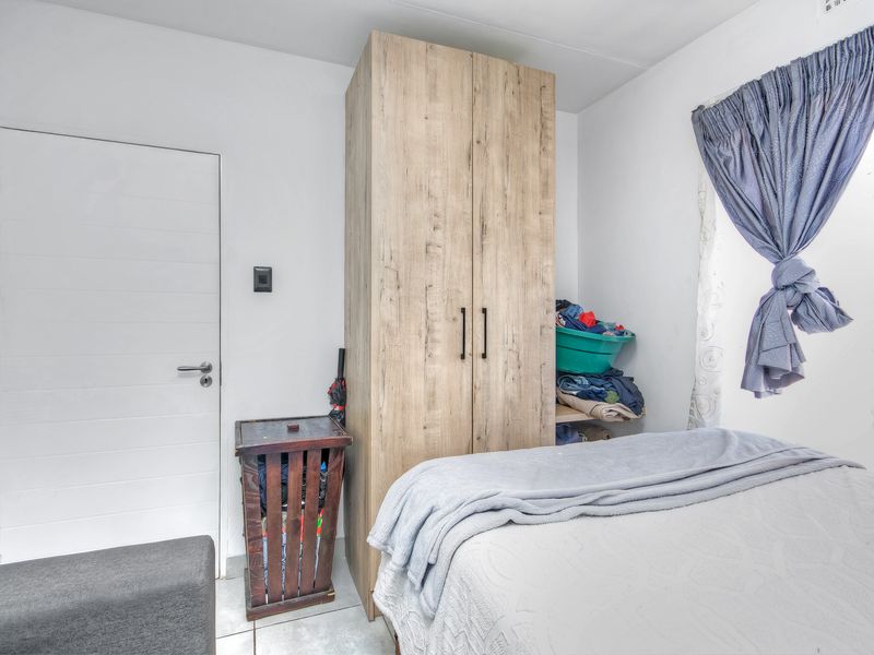 A bedroom featuring tiled flooring and a built-in wooden wardrobe, providing functional storage space.