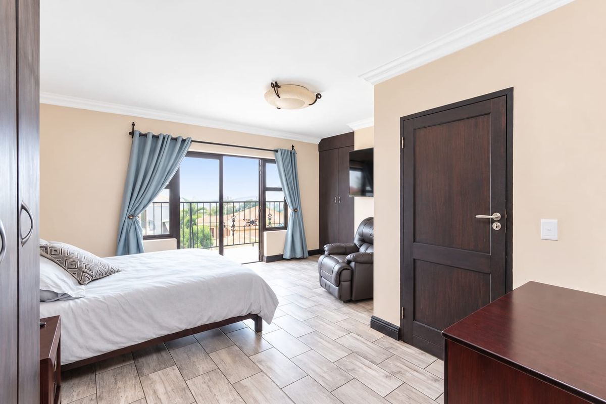 Spacious bedroom featuring tiled flooring, built-in cupboards, and a sliding glass door leading to a private balcony with exterior views.