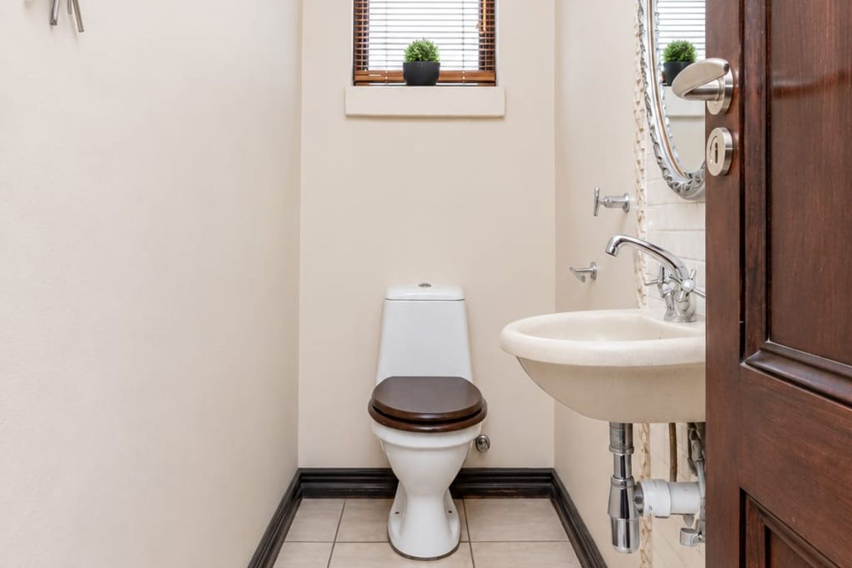 A compact guest bathroom featuring a wall-mounted basin, modern toilet, tiled flooring, and neutral wall finishes.