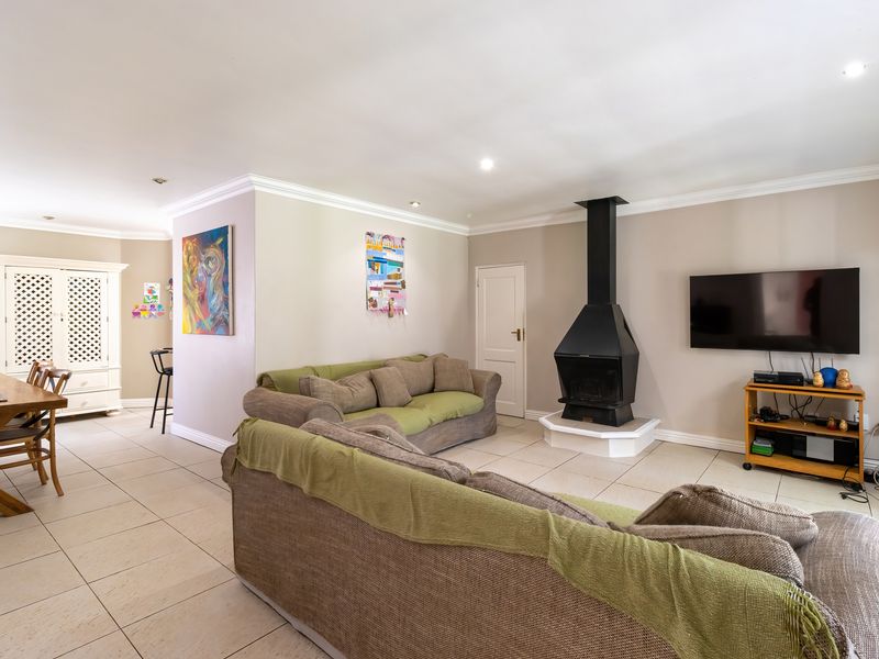 Spacious open-plan living and dining area featuring tiled flooring, recessed lighting, and a prominent freestanding fireplace.