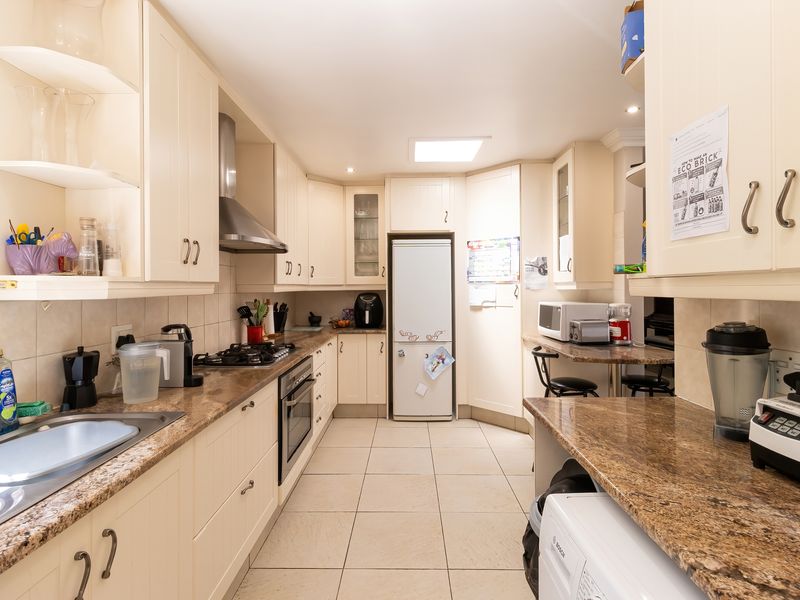 A functional kitchen featuring cream cabinetry, granite countertops, a gas hob, built-in oven, and a skylight for natural illumination.
