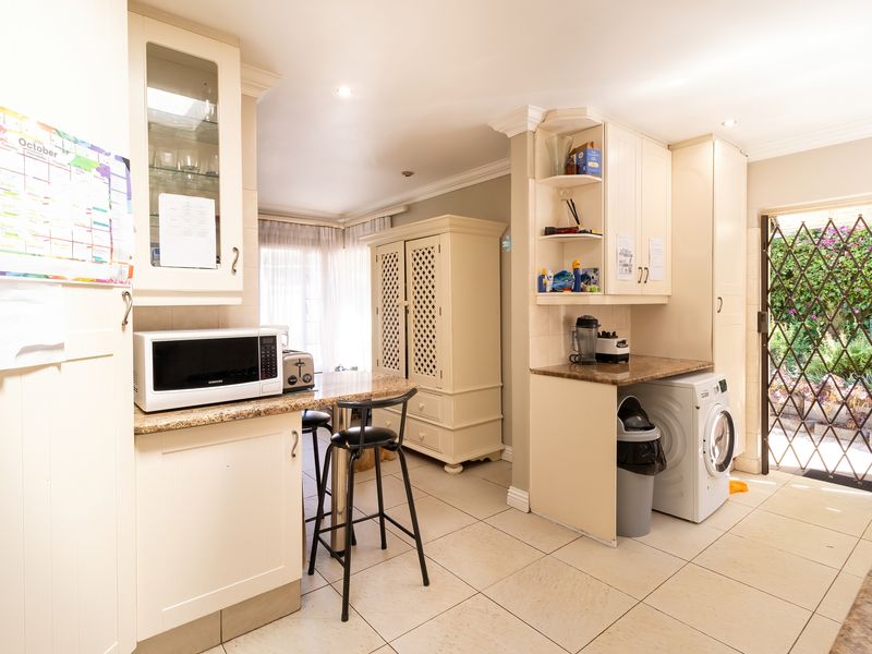 Functional kitchen area featuring built-in cabinetry, granite countertops, tiled flooring, and direct access to the outdoor area through a security gate.