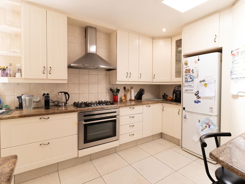 A functional kitchen featuring cream cabinetry, granite countertops, a gas hob, built-in oven, and tiled flooring with a neutral backsplash.