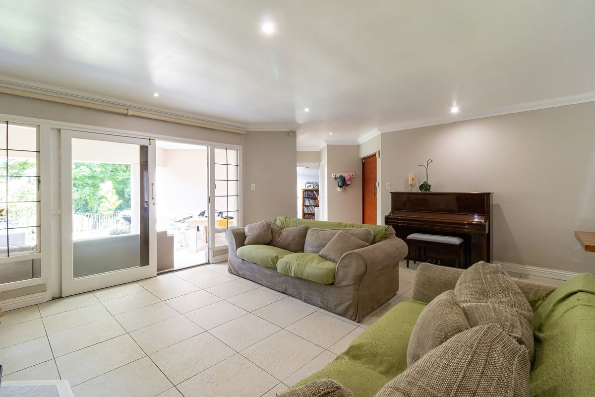 Spacious living room featuring neutral tiled flooring, recessed downlighting, and large sliding glass doors providing direct access to the outdoor patio area.