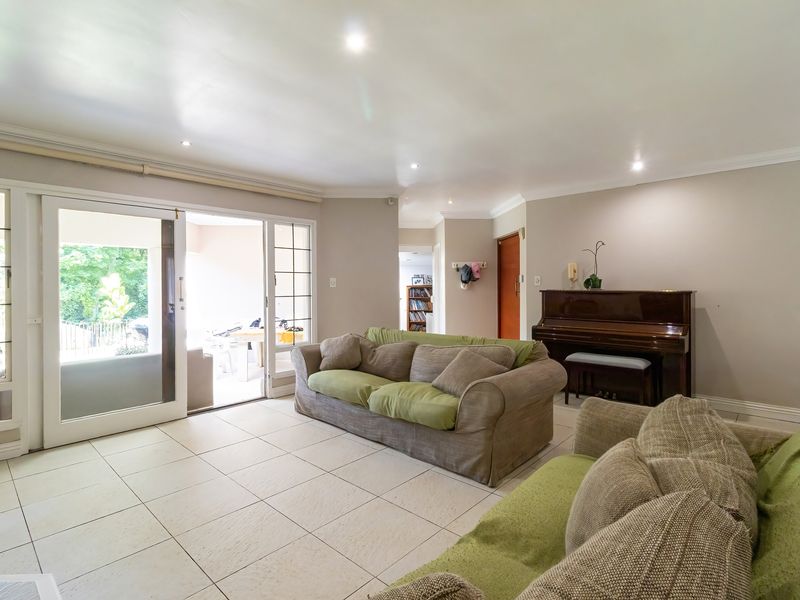 Spacious living room featuring neutral tiled flooring, recessed downlighting, and large sliding glass doors providing direct access to the outdoor patio area.