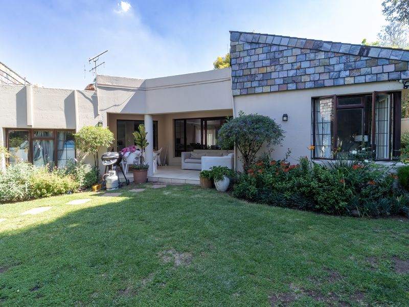 Rear view of the property featuring a covered patio, sliding glass doors, and a well-established garden with a unique tiled roof section.
