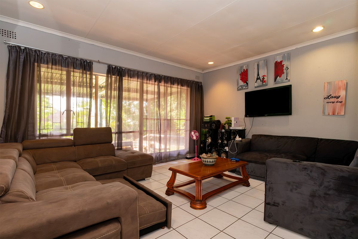 A spacious living room featuring tiled flooring, recessed lighting, and large sliding glass doors that provide access to the outdoor area.