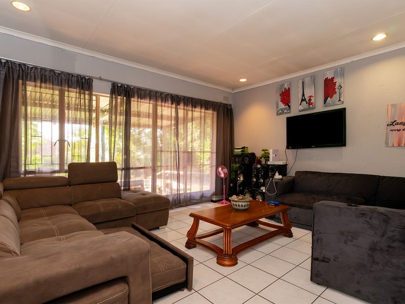 A spacious living room featuring tiled flooring, recessed lighting, and large sliding glass doors that provide access to the outdoor area.
