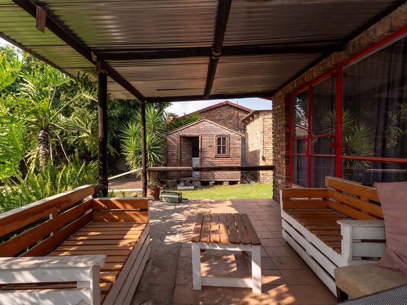 Covered outdoor patio area featuring tiled flooring, brick wall construction, and direct access to the rear garden and detached wooden shed.