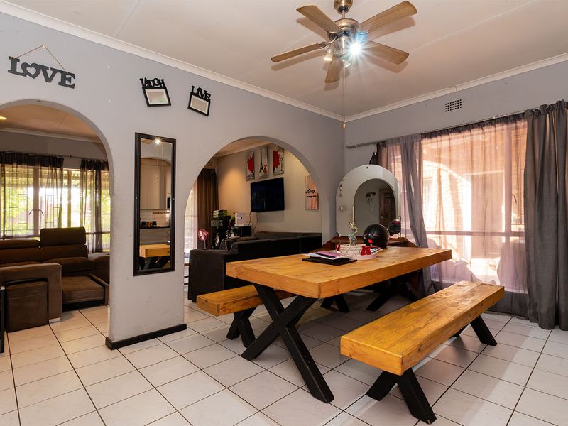 Open plan living and dining area featuring tiled flooring, arched architectural details, and a ceiling fan, providing a versatile space for family living.