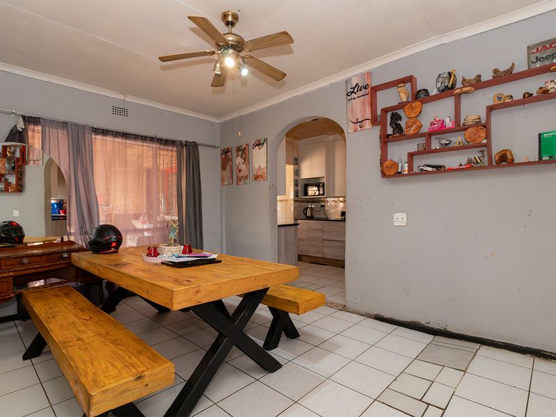 Dining area featuring tiled flooring, a ceiling fan, and an arched entryway leading to the kitchen.