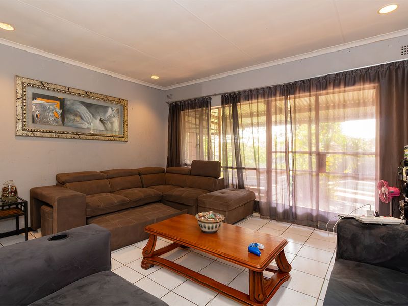 A comfortable living room featuring tiled flooring, recessed downlighting, and a large sliding glass door providing access to the outdoor area.