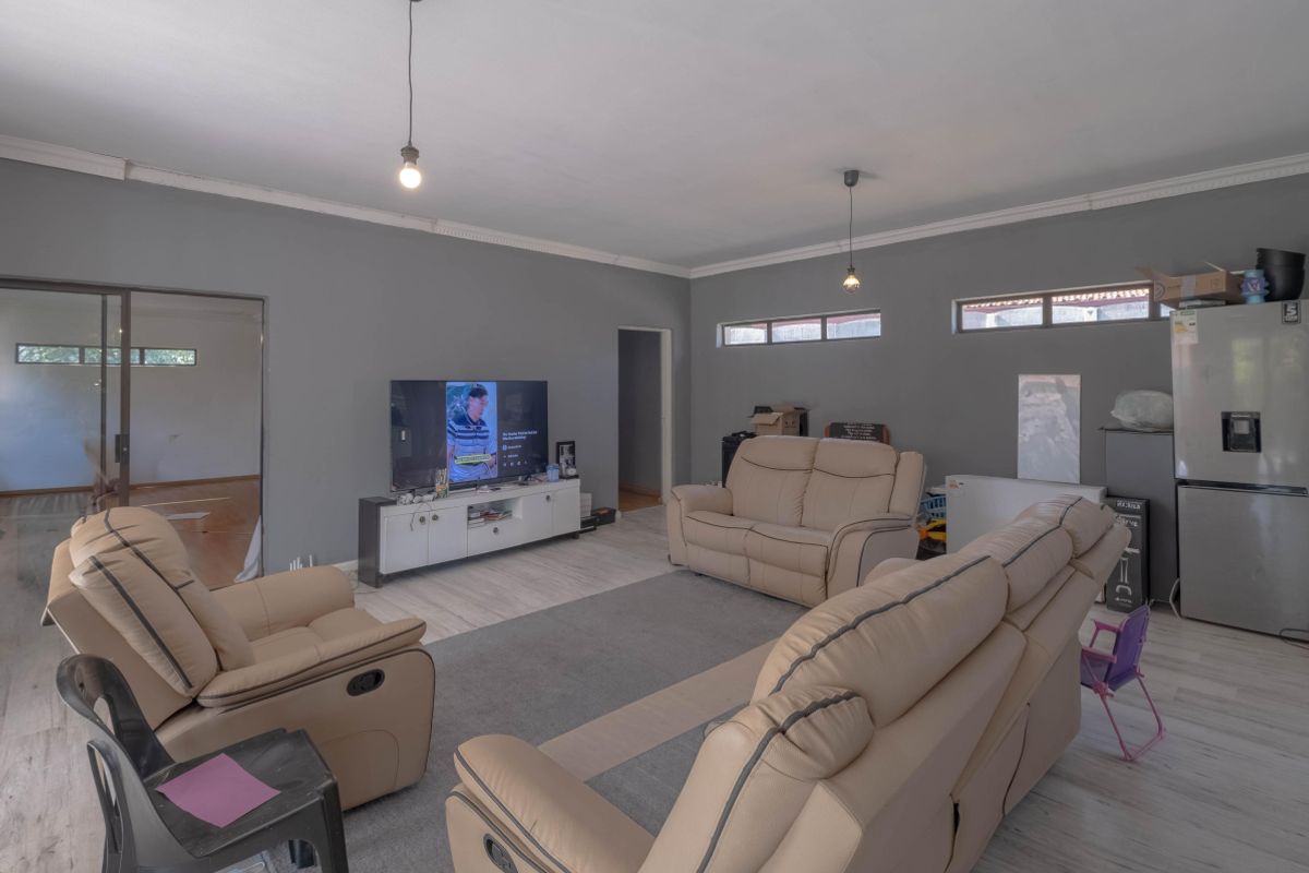 Spacious living room featuring laminate flooring, high-level windows for natural light, and neutral grey walls with decorative cove cornicing.