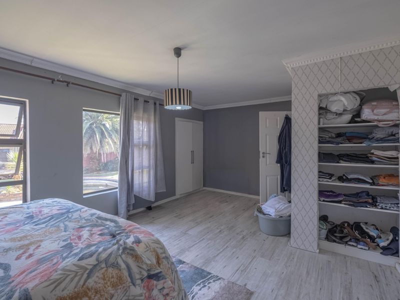 Spacious bedroom featuring laminate flooring, built-in cupboards, and large windows providing natural light and garden views.